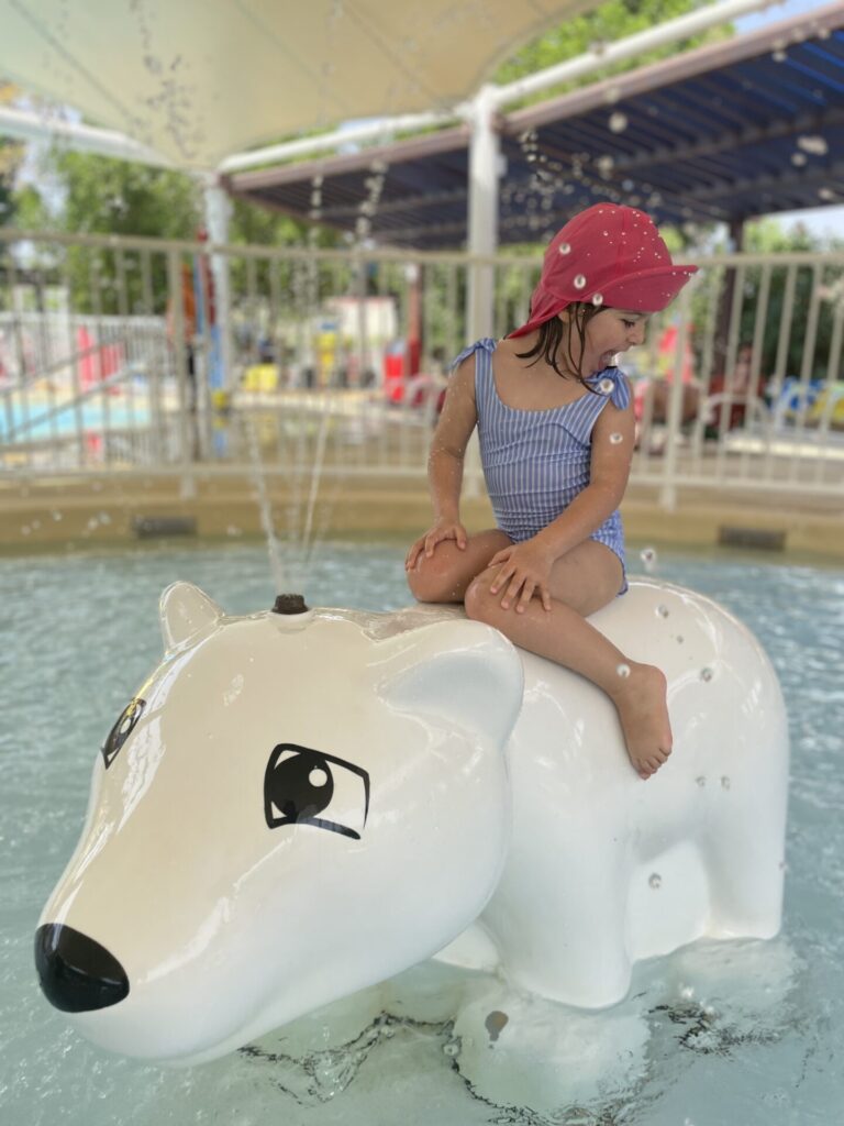 A girl sits on a play bear in the water in the play area of Legoland Dubai