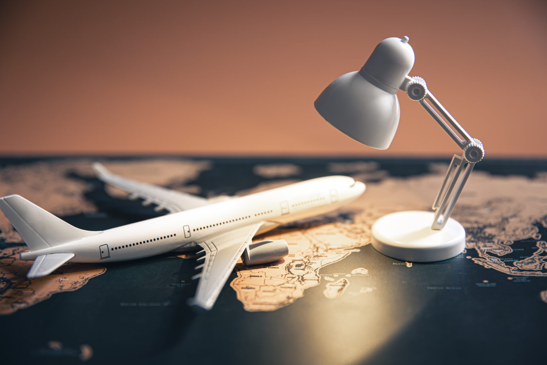 A Small Table Lamp And A Plane On A World Map